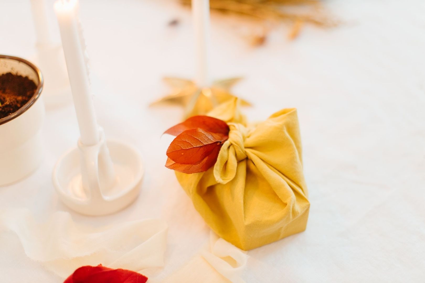 Prezent owinięty w żółtą tkaninę furoshiki z jesiennymi liśćmi